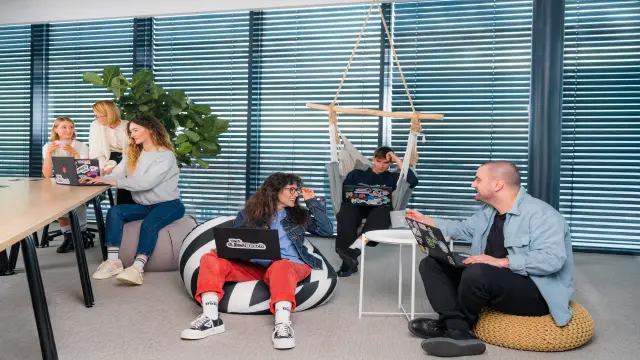 Un grup de oameni diverși țin eșarfe cu mesajul „Join the Team“. O persoană le face semn celor care urmăresc să se alăture grupului.