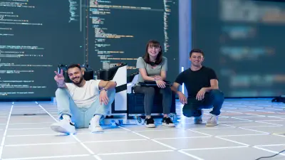 Doi asociați Bosch, o femeie și un bărbat, stau pe o canapea și au o conversație prietenoasă. Femeia are un laptop în brațe. Ambii poartă tricouri cu imprimeu "#LikeABosch".